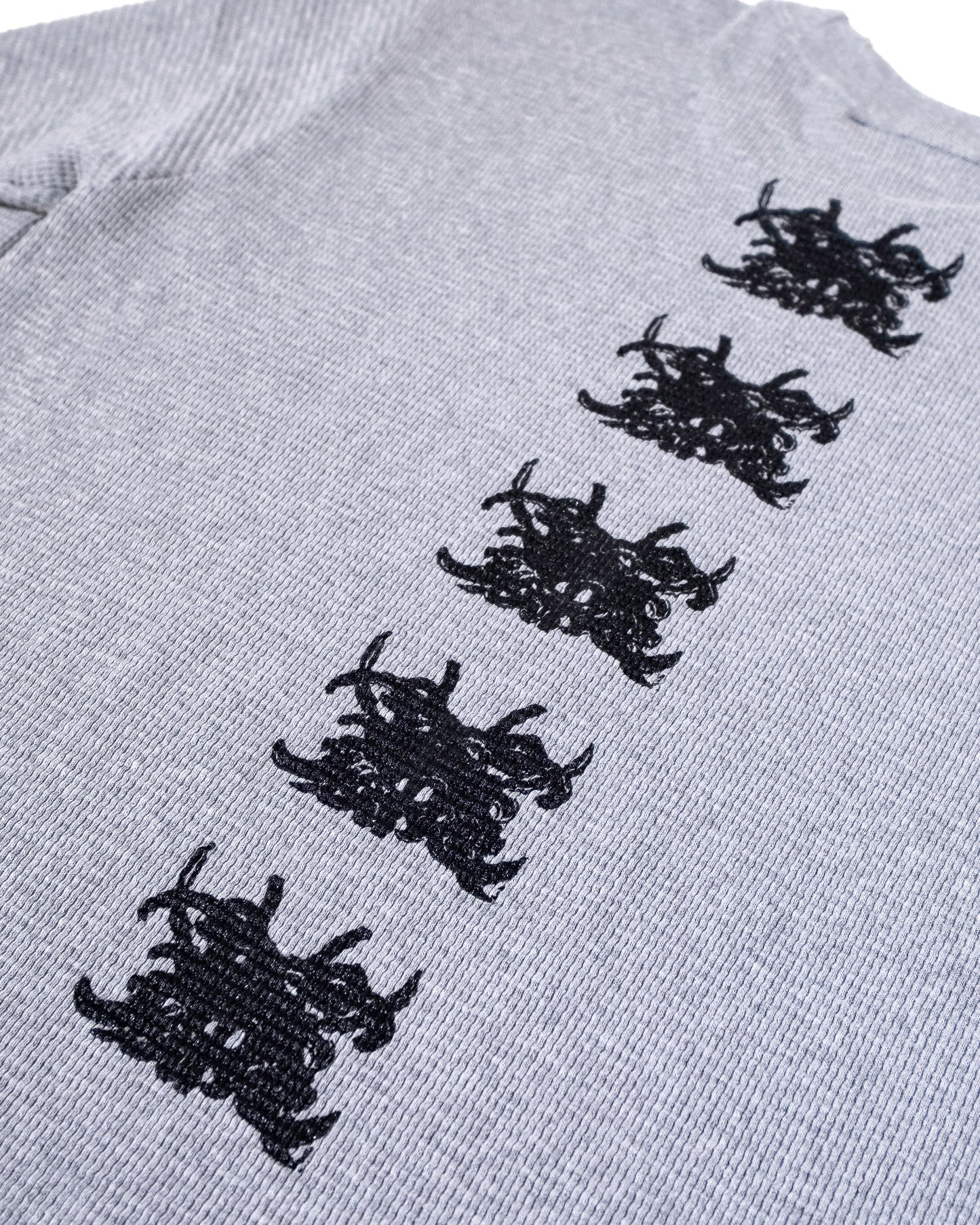 Gray sweater with black embroidered patterns on a white background