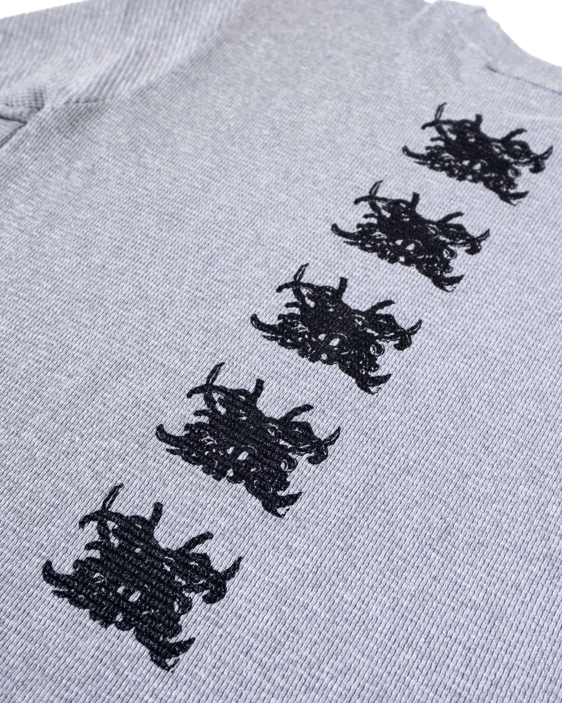 Gray sweater with black embroidered patterns on a white background